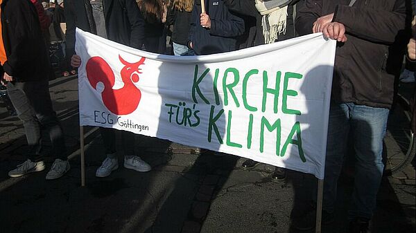 Demo-Banner mit Rotem Hahn und Spruch "Kirche fürs Klima"